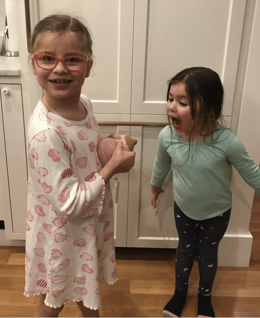 Two young children holding a knitted breast for demonstrating breastfeeding