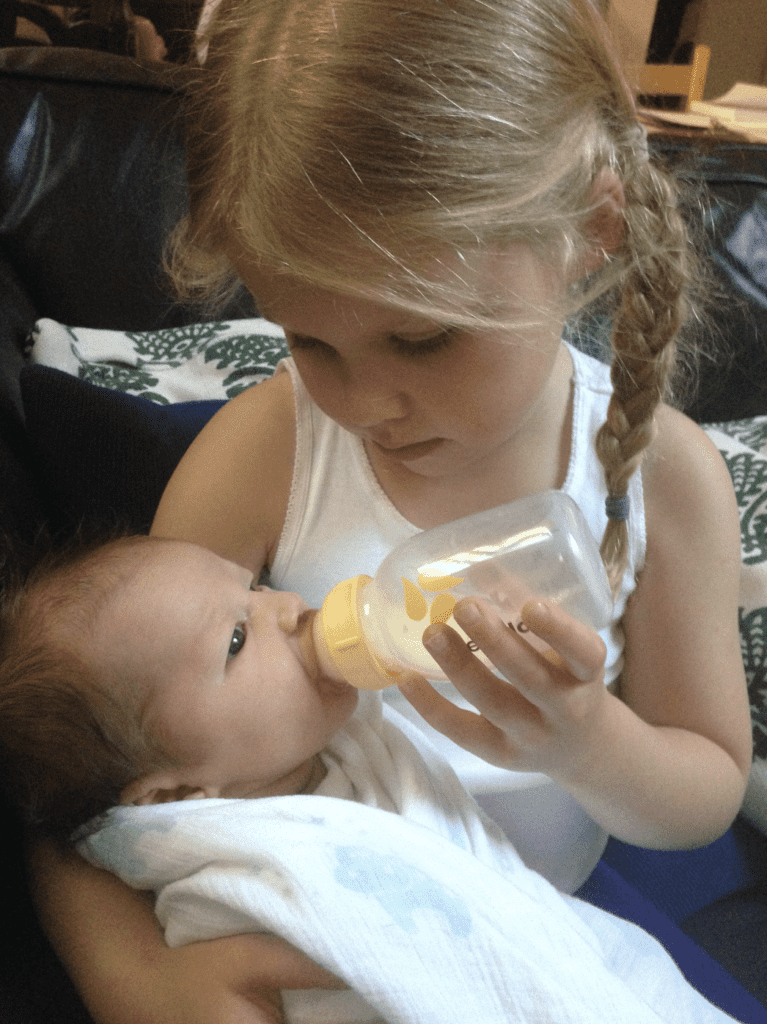 Preschool aged girl bottle feeding baby